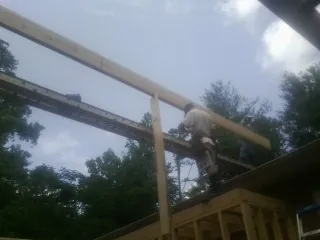 Carpenter setting a ridge beam over a new addition frame — Ice Dam Removal by Roofing Brothers in Pineview