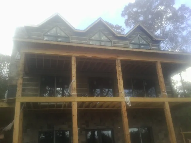 Dormers and porch framing on a large log home under construction — Roof Coating work by our crew in Pineview