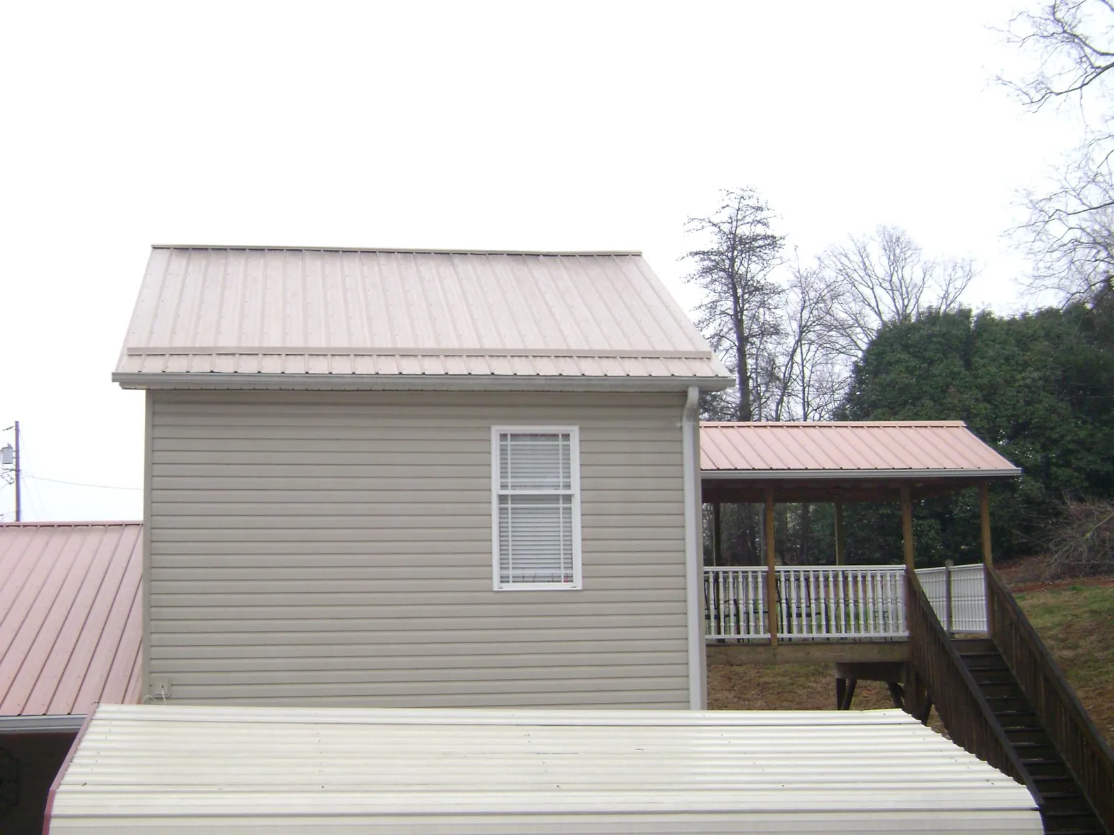 Tan metal roofs on a two story addition and attached porch, from a Roof Replacement job in Pineview